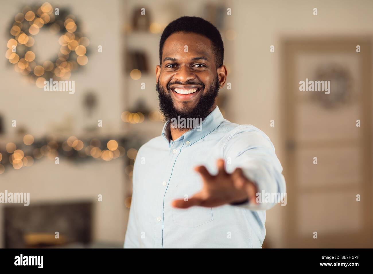 Black man with beard reaching out hand while standing at home Stock Photo
