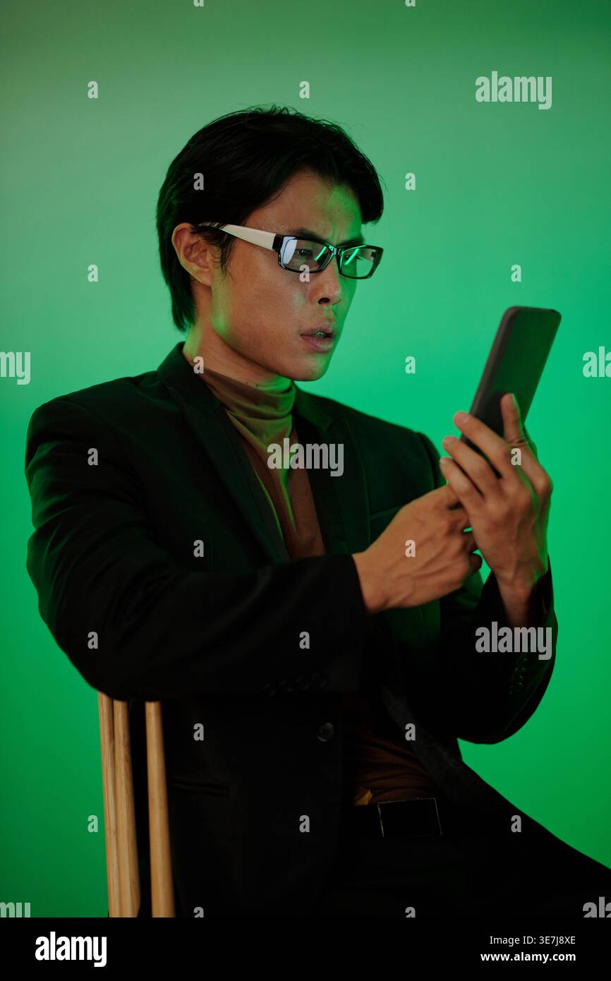Shocked Asian man reading text message on smartphone Stock Photo