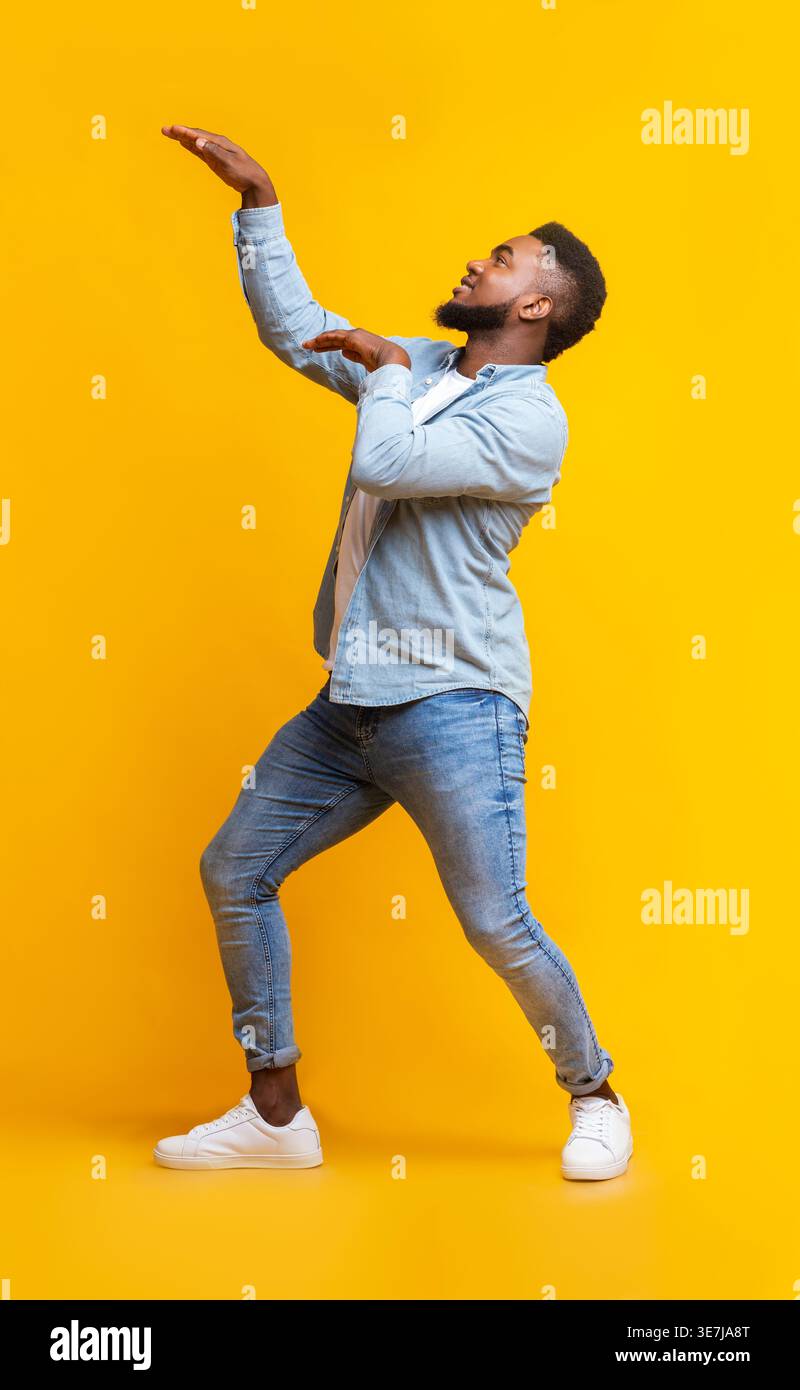 Black man having fun dancing against yellow background in studio Stock Photo