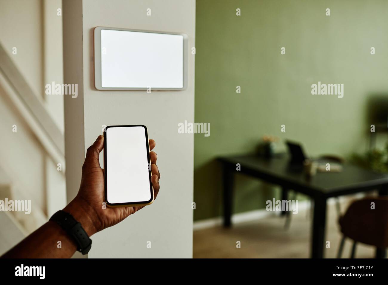 Black man using smartphone while connecting to smart home system standing indoors Stock Photo