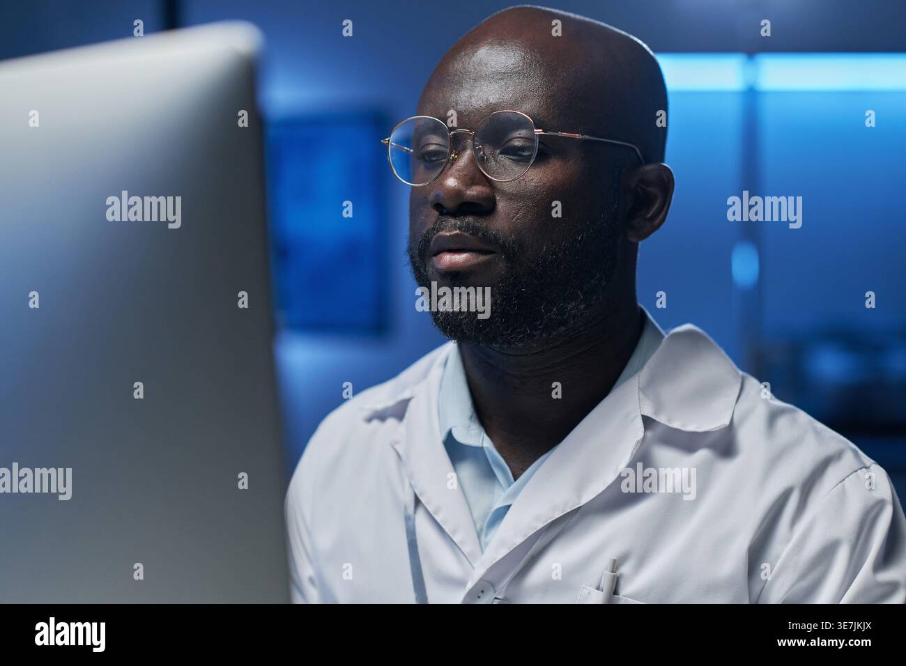 Black male computer engineer in eyeglasses looking at computer screen while sitting in laboratory Stock Photo