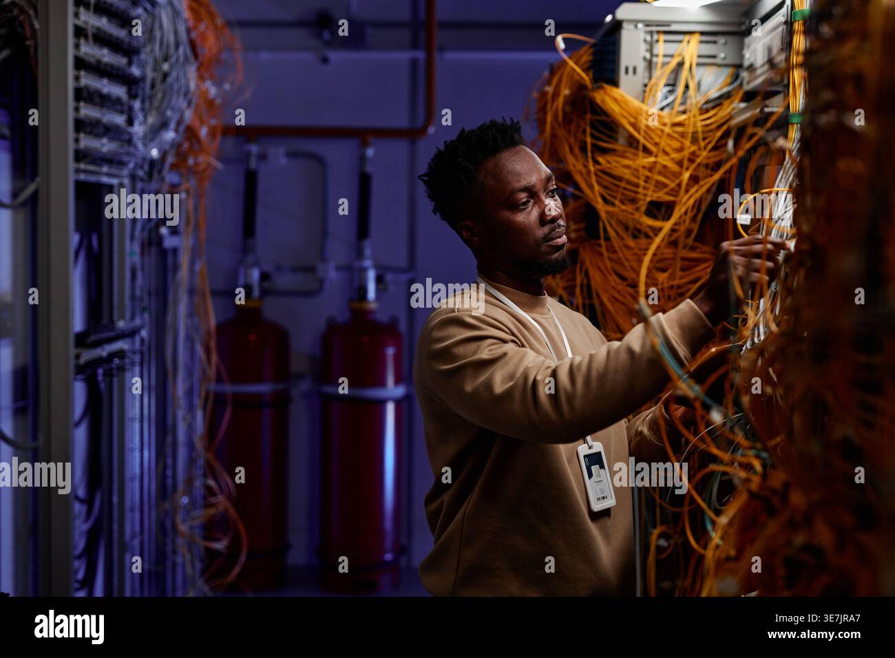 Black male system administrator setting up server network and doing maintenance in server room Stock Photo