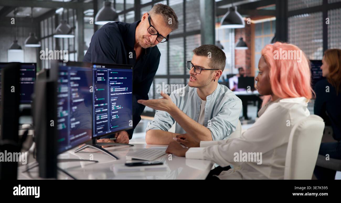 Software Engineer Writes Code Carefully While Collaborating With Colleagues Closely. Stock Photo