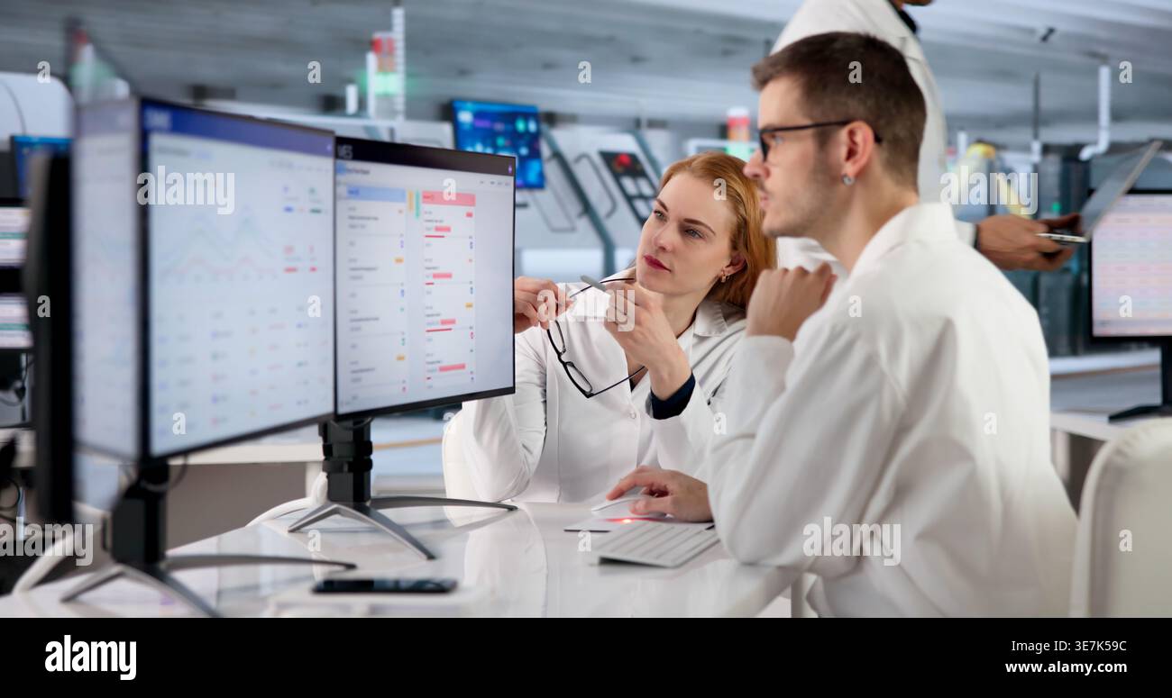 Factory Manager Monitors Real-time Production Tracking On Multiple Screens. Stock Photo