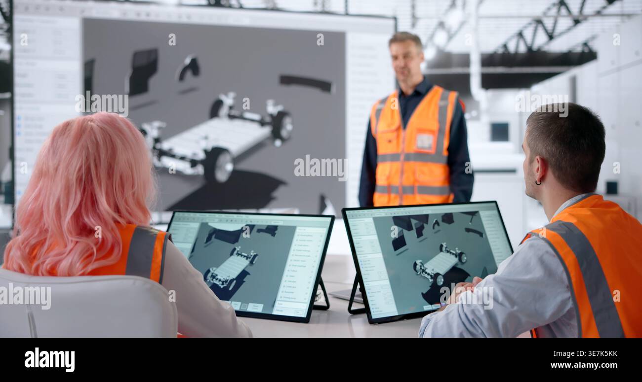Engineer Explains New Electric Car Model Using Tablet During Team Meeting. Stock Photo