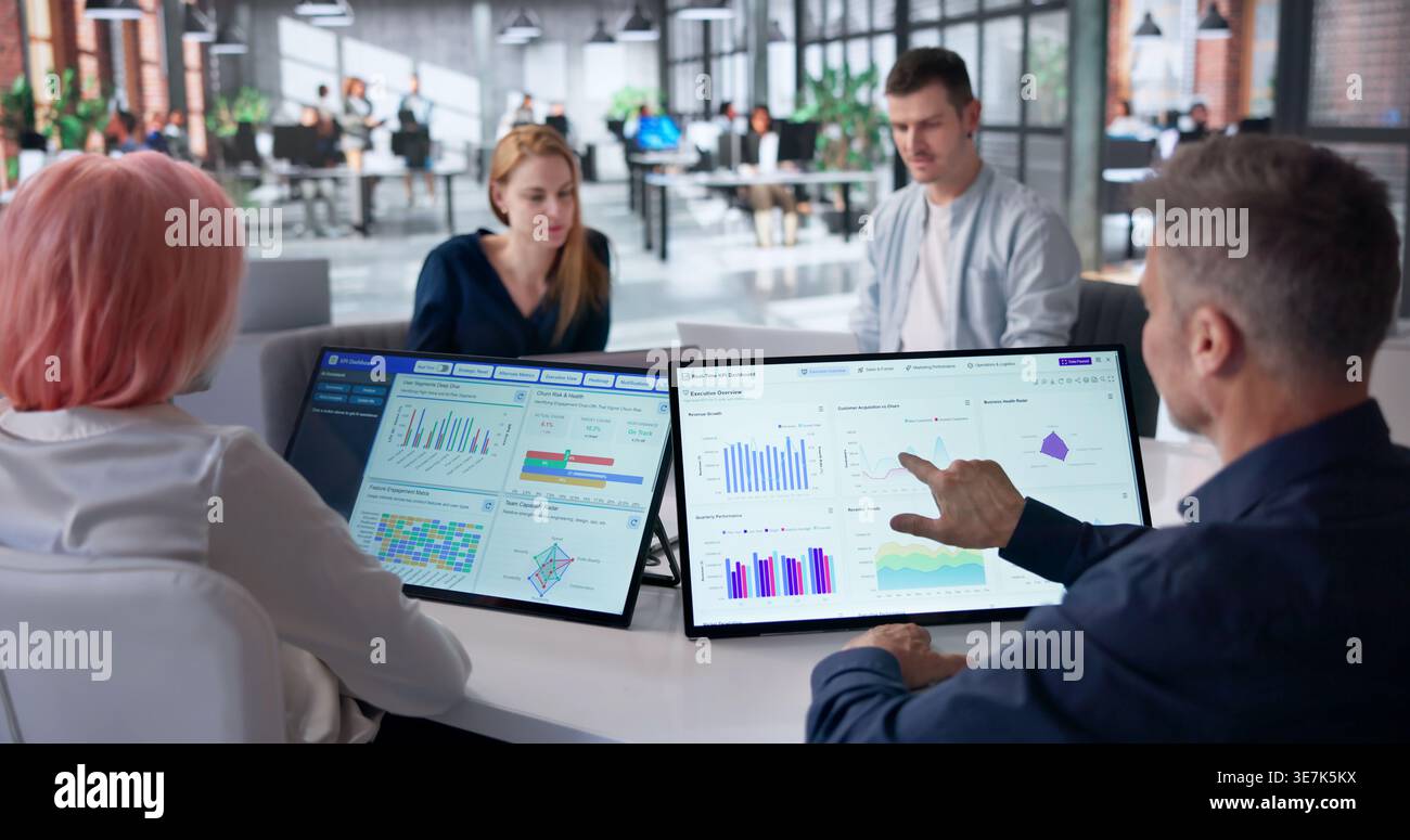 Data Analysts Discuss KPI Dashboards While Reviewing Company Performance Graphs. Stock Photo