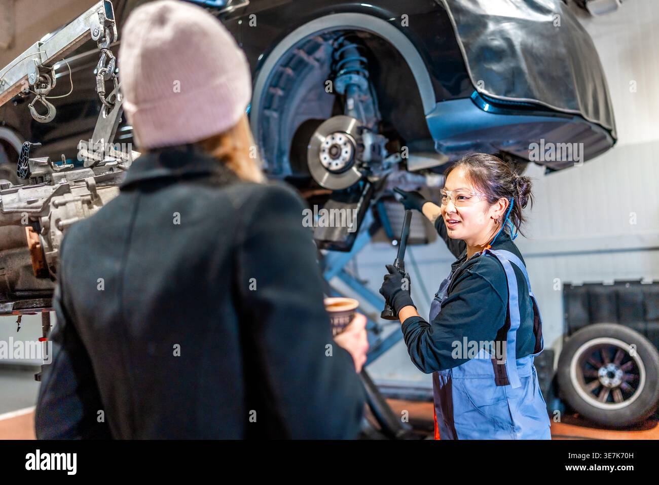 Asian female mechanic discussing vehicle maintenance with female ...