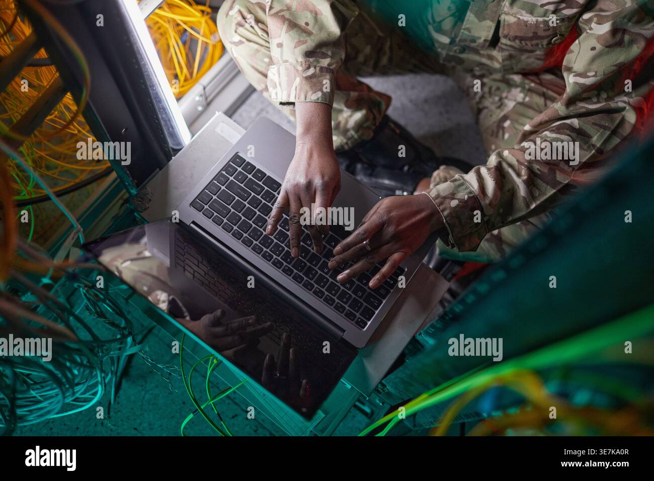 Black female soldier using laptop while sitting in server room Stock Photo
