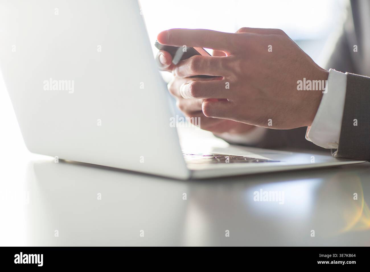 Chinese businessman using smartphone while sitting at table with laptop in office Stock Photo