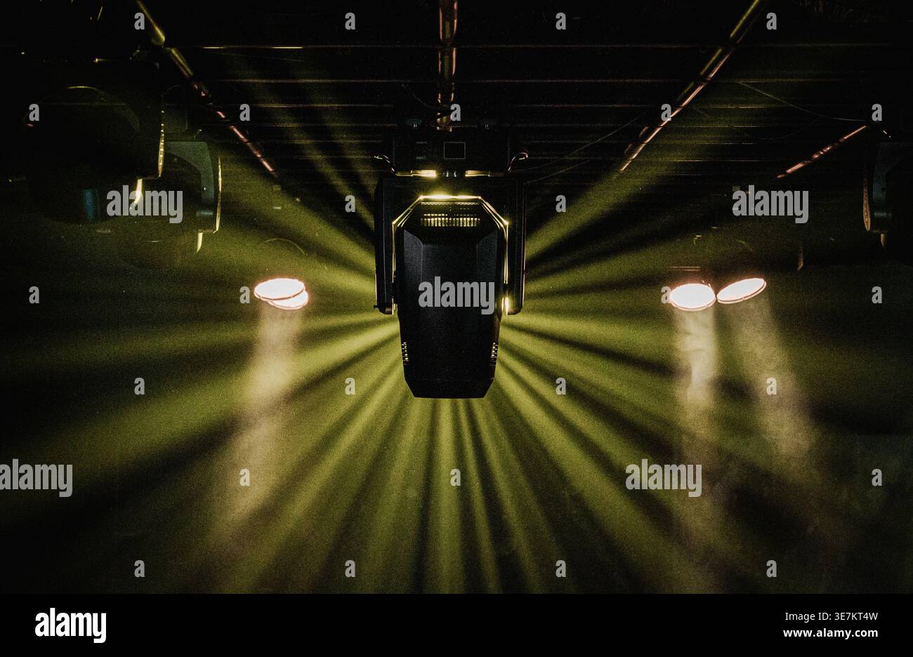 Stage lighting rig projecting dramatic beams of light in a dark concert or performance venue. Stock Photo