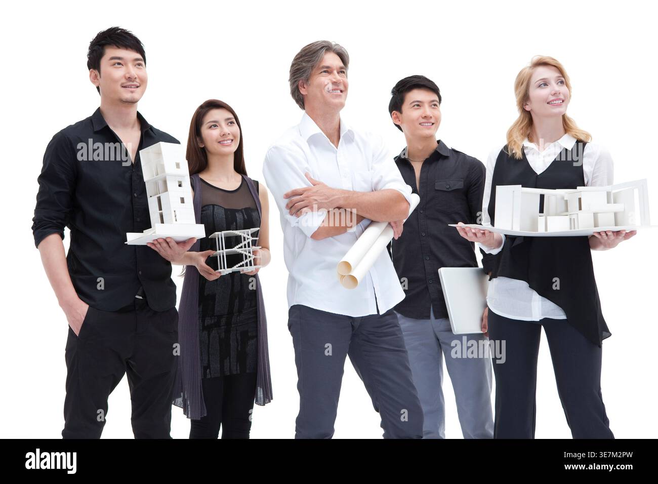 Chinese and caucasian architects holding architectural model looking away while standing against white background in studio Stock Photo