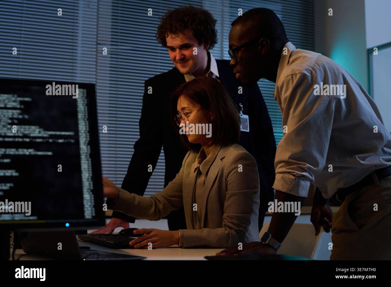 Diverse group of programmers developing new code for computer program together working overtime in office Stock Photo