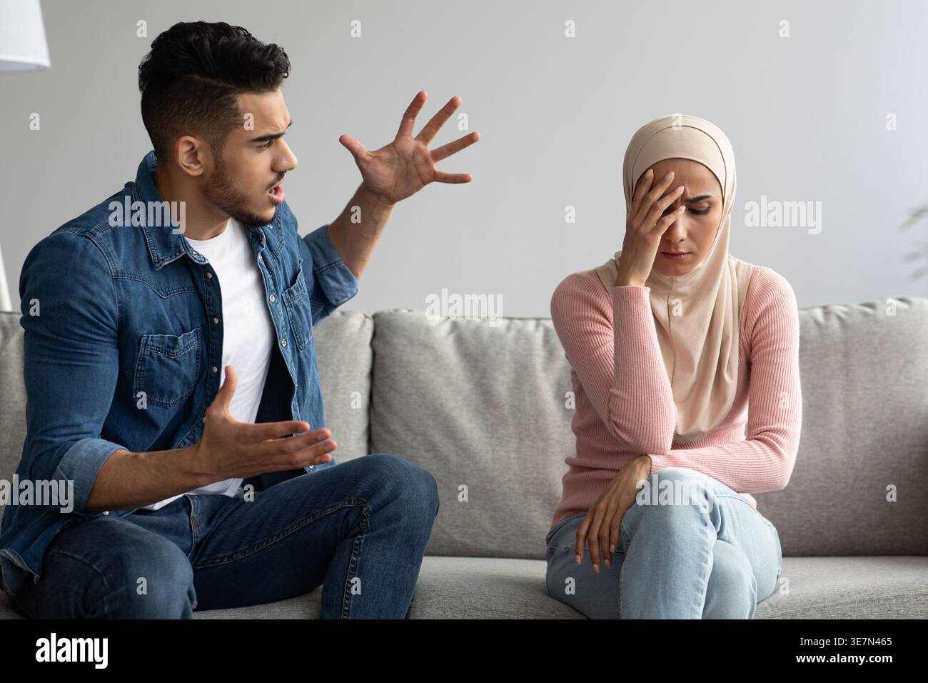 Middle Eastern man yelling at his irritated girlfriend while sitting on sofa at home Stock Photo
