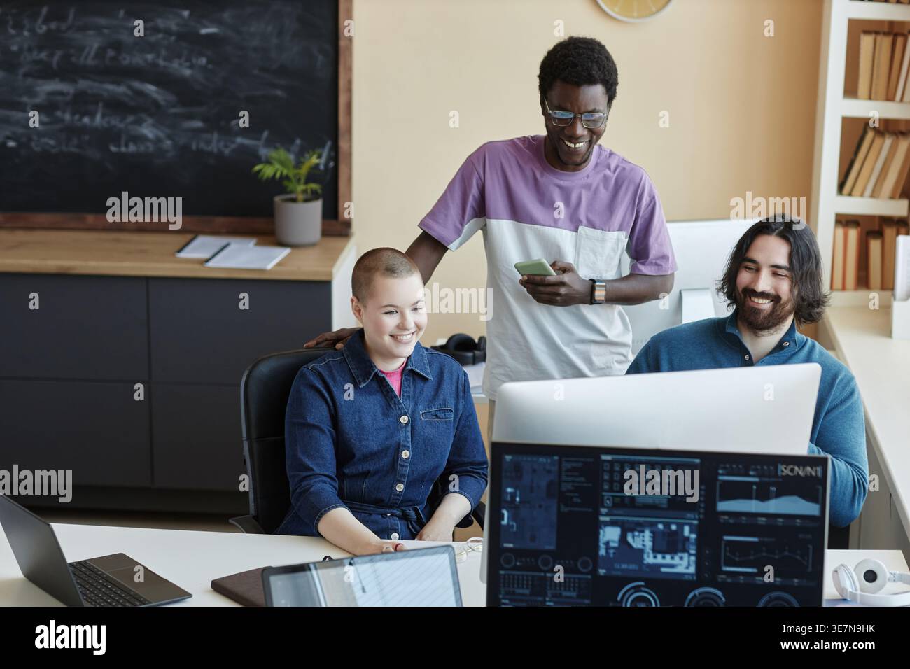 Group of programmers looking at computer screen discussing their work ideas in office workplace Stock Photo