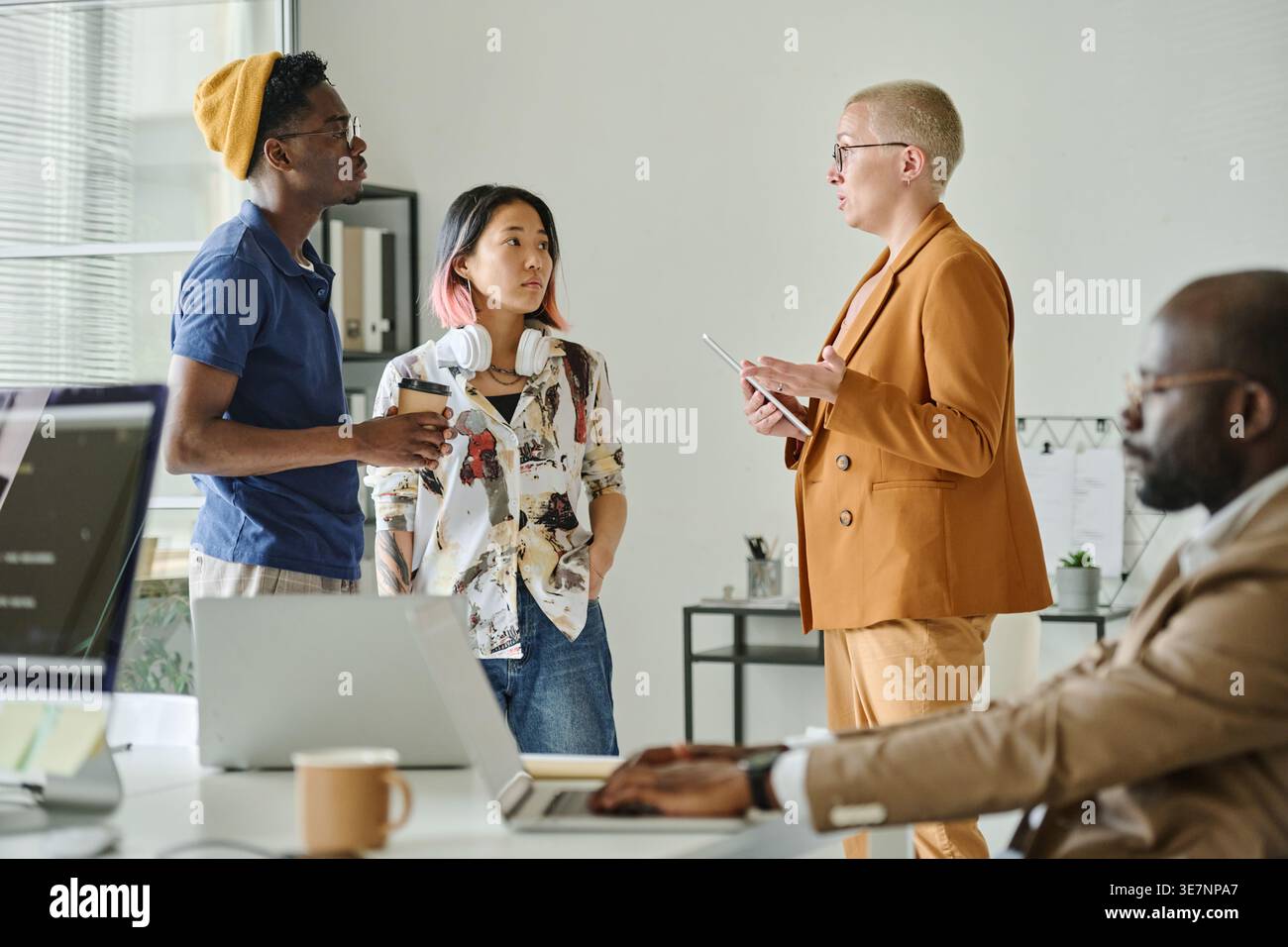 Diverse group of programmers discussing new project while standing in office Stock Photo
