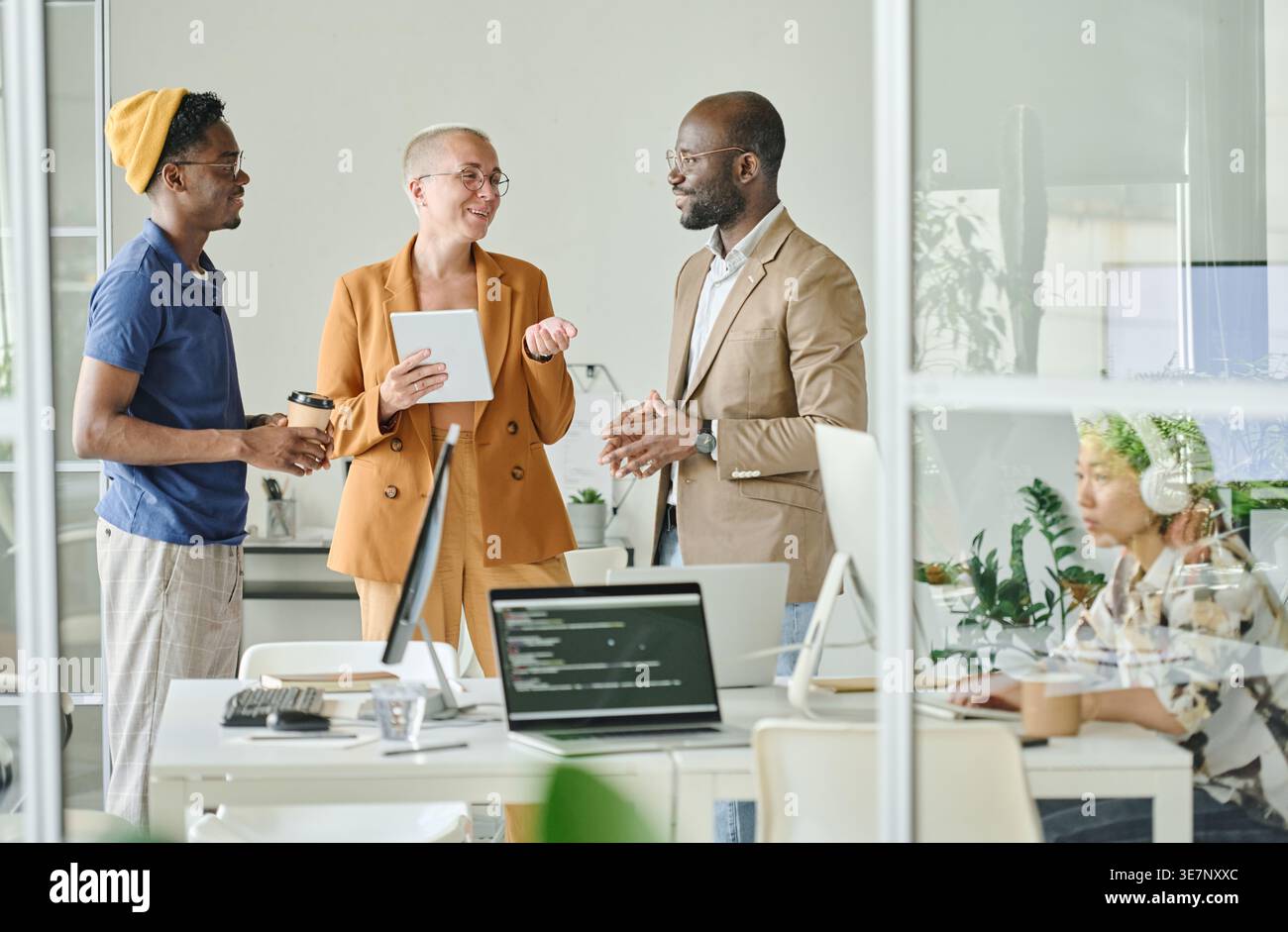 Smiling Diverse group of programmers discussing new project while standing in office Stock Photo
