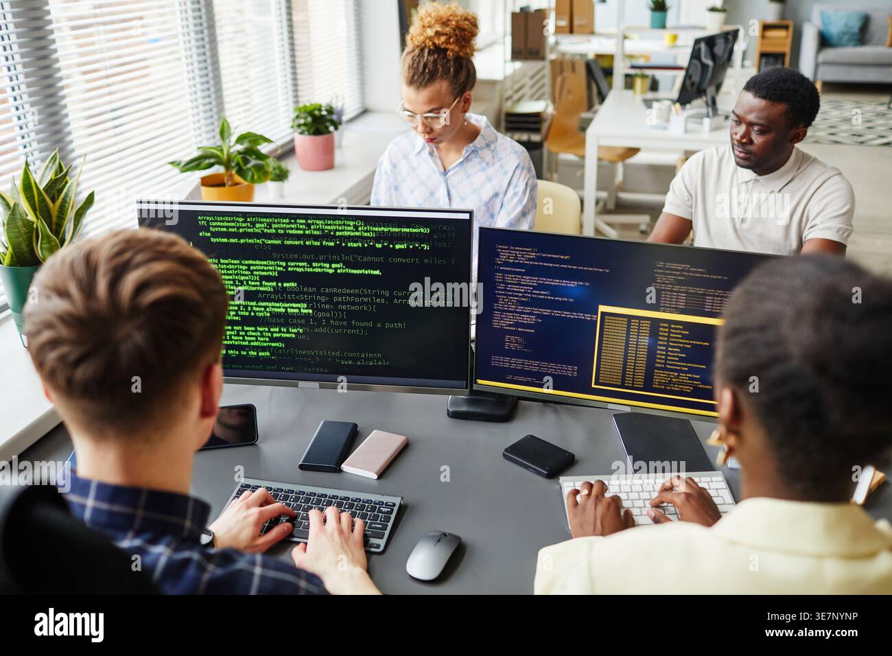 Diverse group of programmers working on computers sitting at  table in office Stock Photo