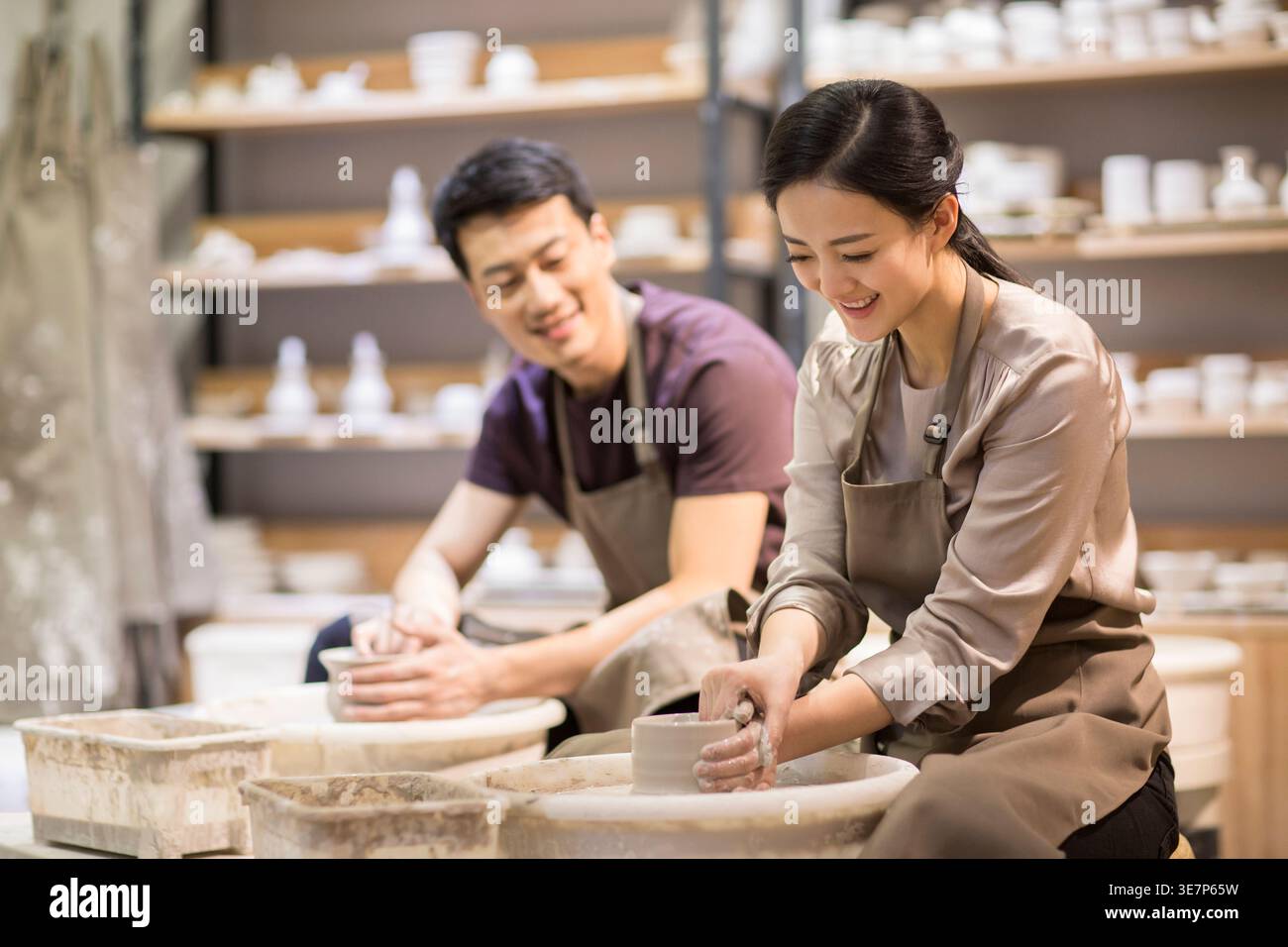 Chinese man teaching her wife making ceramic pot from clay in pottery workshop Stock Photo