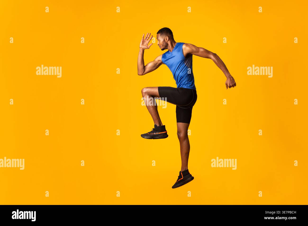 Black man jumping against yellow background in studio Stock Photo