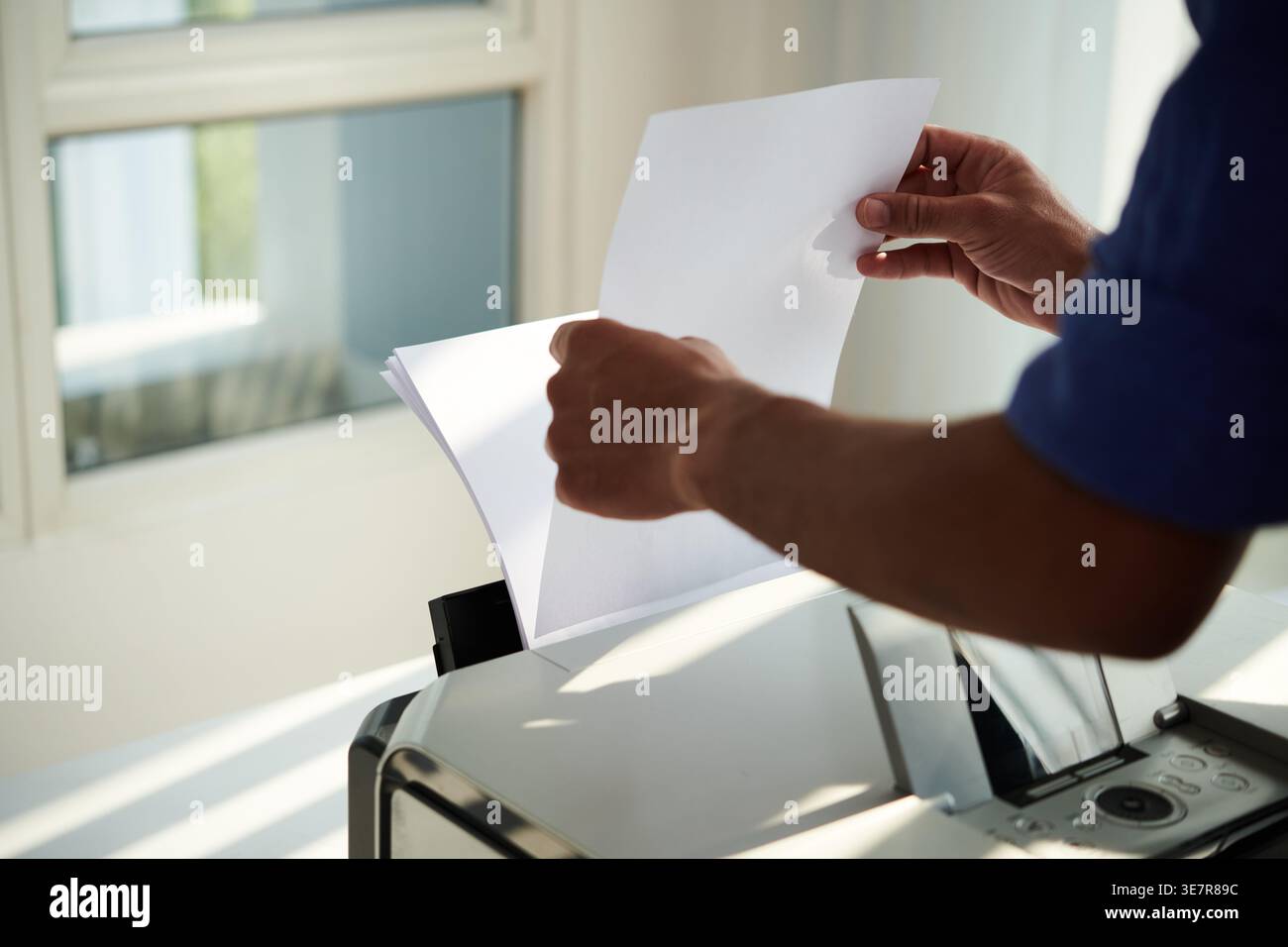 Hands of Mixed race man putting papers on printer to print documents in office Stock Photo