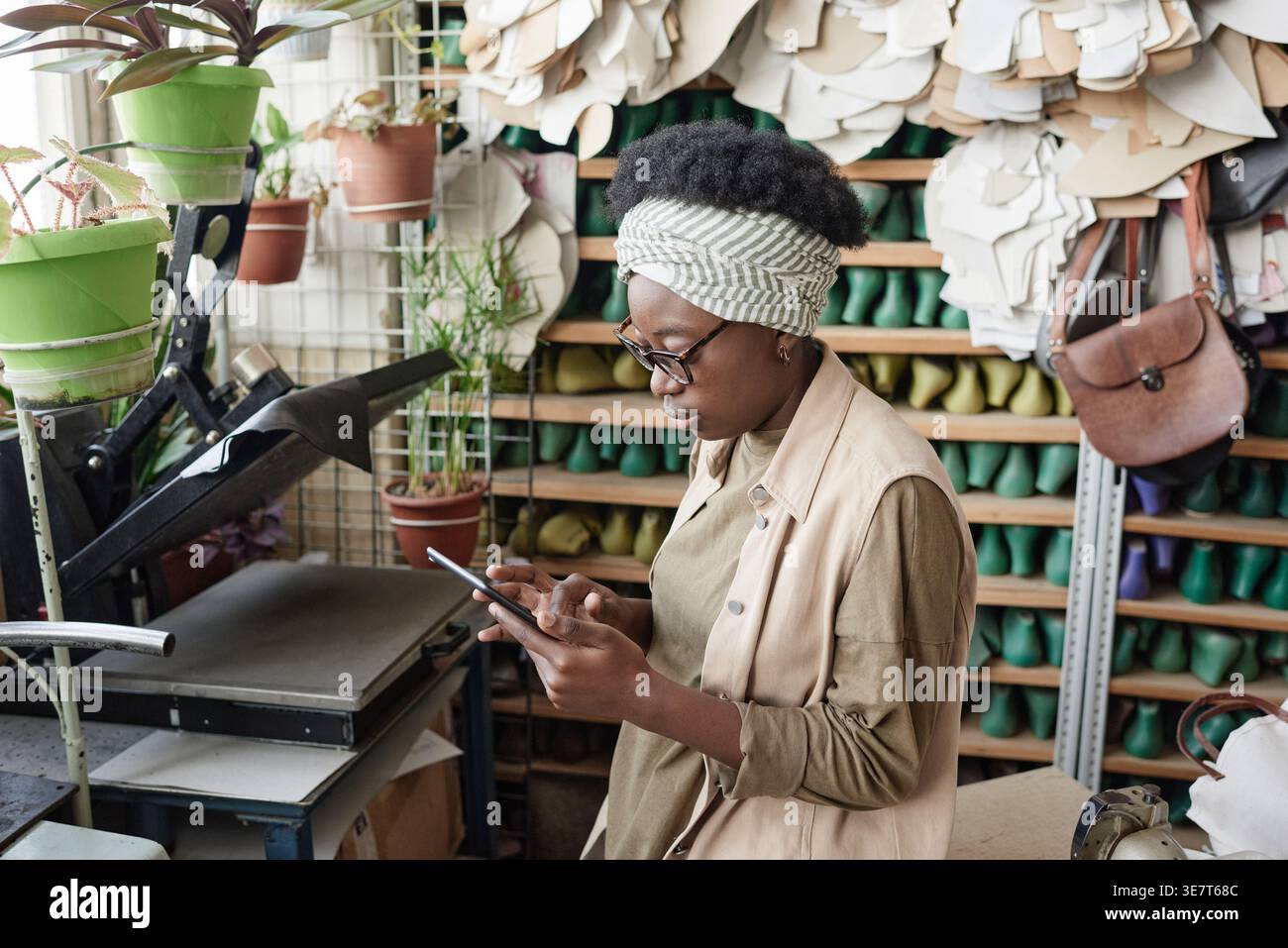 Black female tailor wearing eyeglasses using tablet while standing in workshop Stock Photo