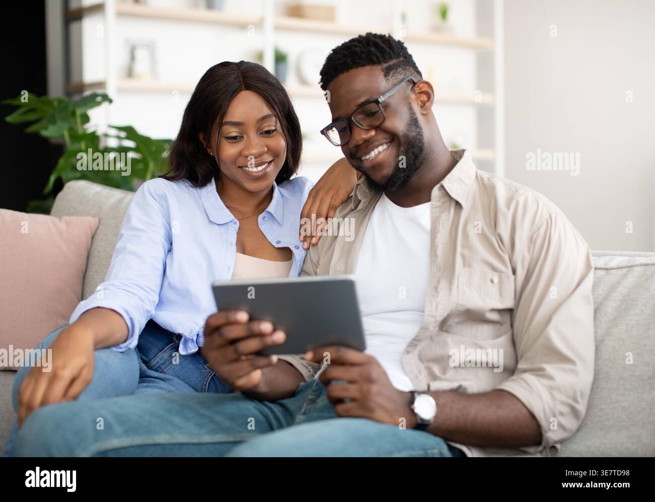 Black couple using tablet together sitting on sofa at home Stock Photo