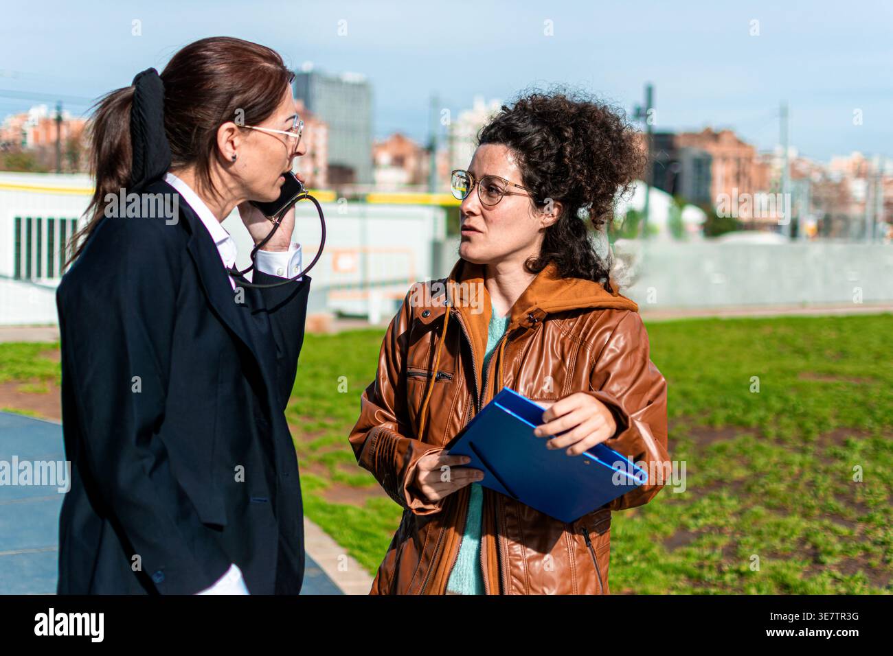 Businesswomen talking outdoors discussing project details Stock Photo