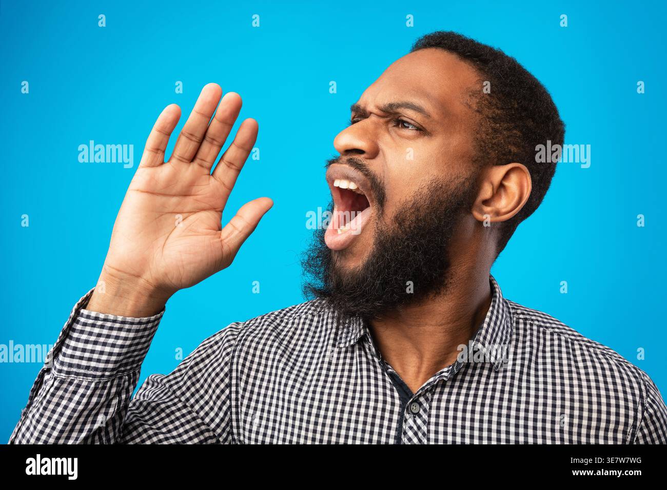 Black man looking away and shouting while standing against yellow background in studio Stock Photo