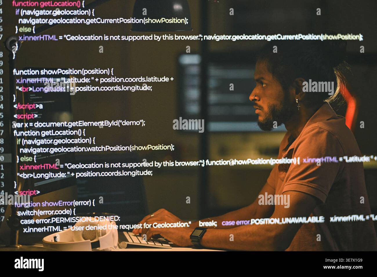 Indian male programmer examining computer codes sitting at table working late at night in office Stock Photo