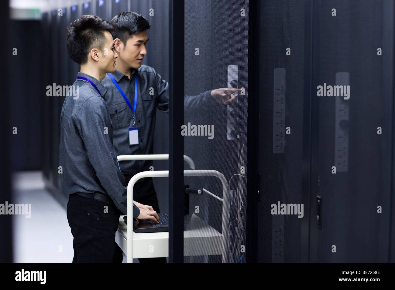Chinese male technicians doing maintenance using laptop in computer room Stock Photo