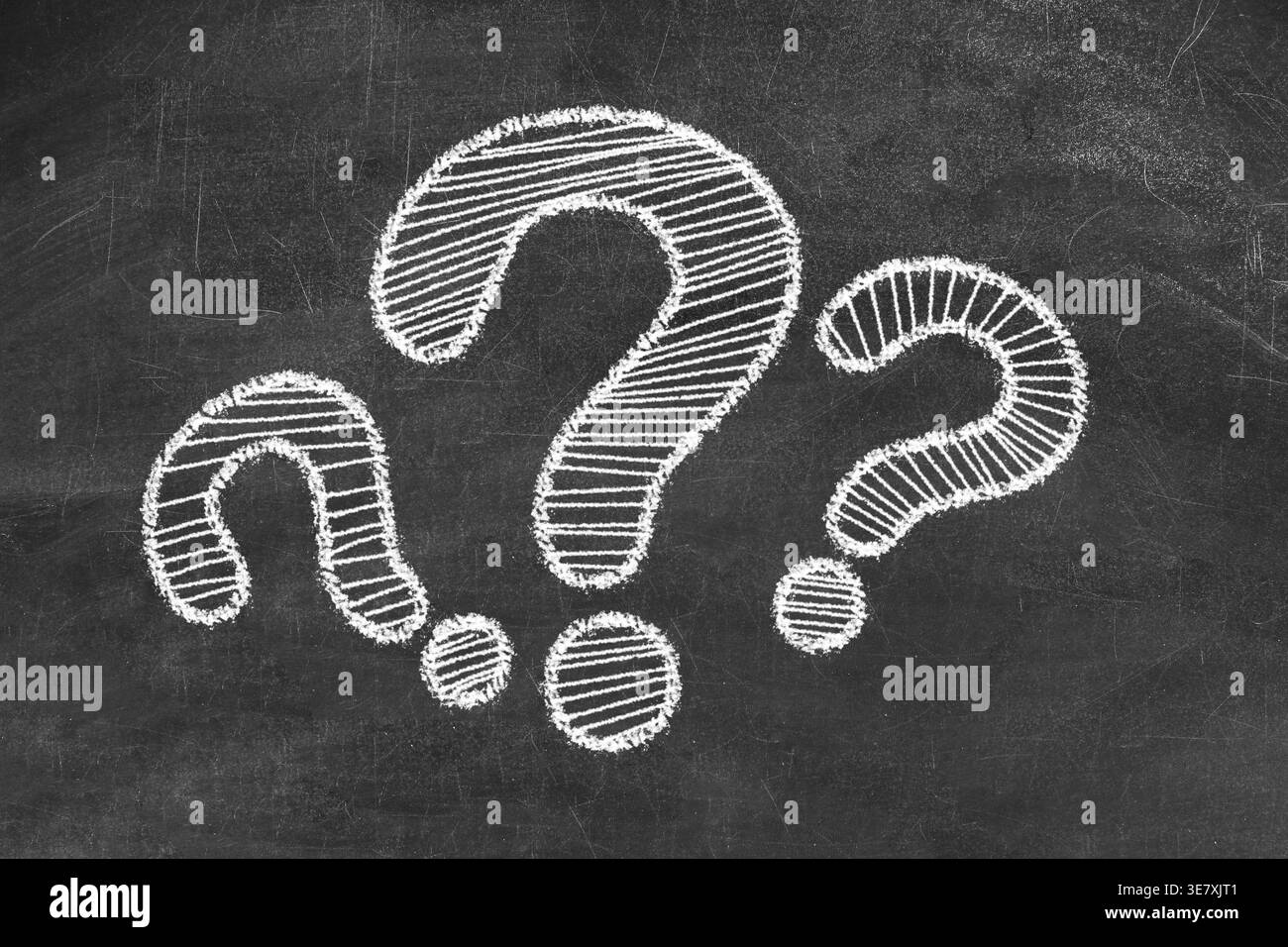 Three question marks drawn on black chalkboard Stock Photo