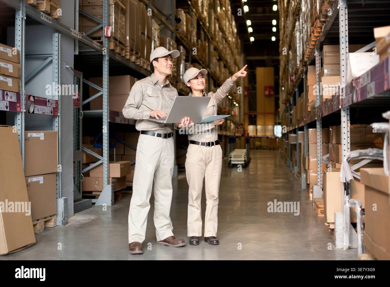 Chinese male and female workers standing and doing inventory together in distribution warehouse Stock Photo