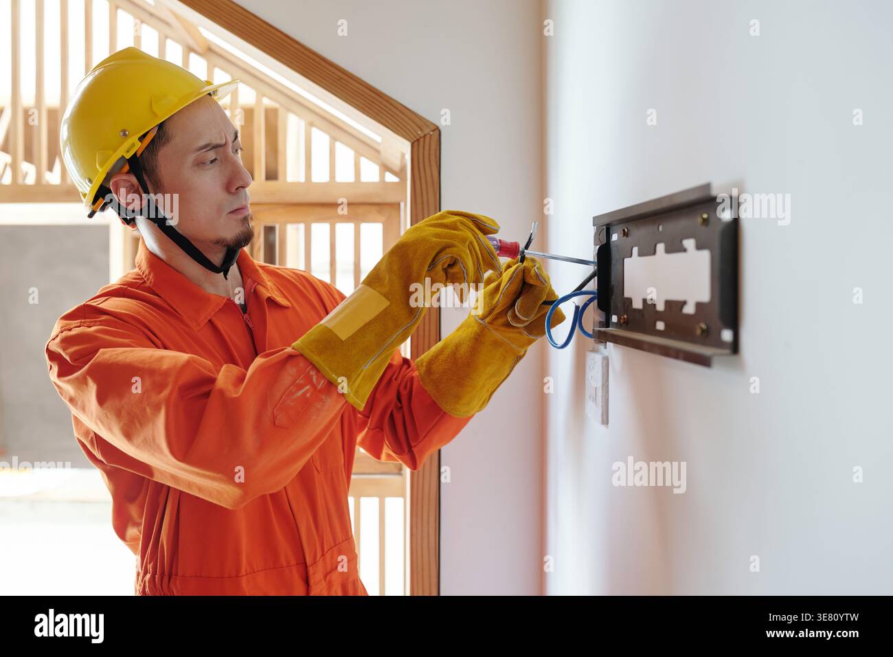 Mixed race male construction worker doing electrical work while standing in construction site Stock Photo