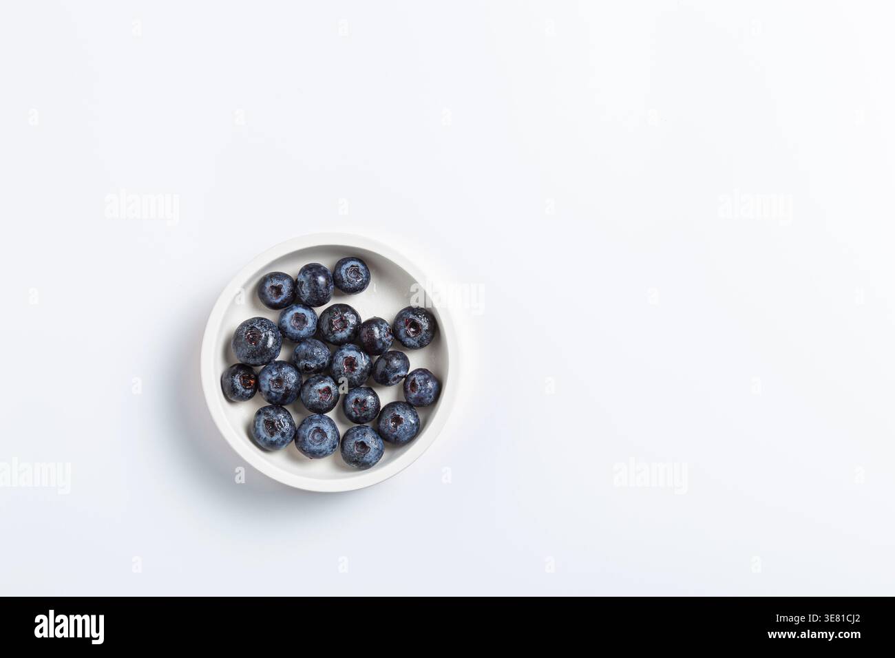 A top-down view of fresh, ripe blueberries gathered in a small white ceramic bowl. Stock Photo