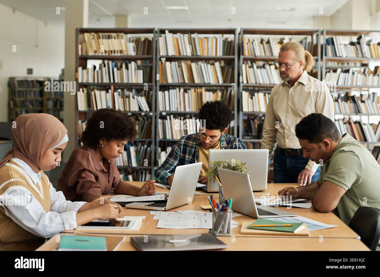 Group of students studying together while sitting at table in library Stock Photo