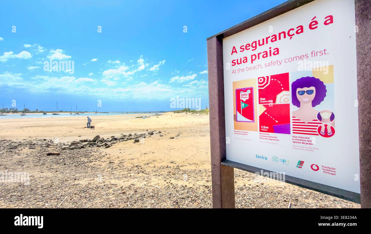 Safety sign board on a beach in Tavira Portugal with instructions in Portuguese and English under a blue sky Stock Photo