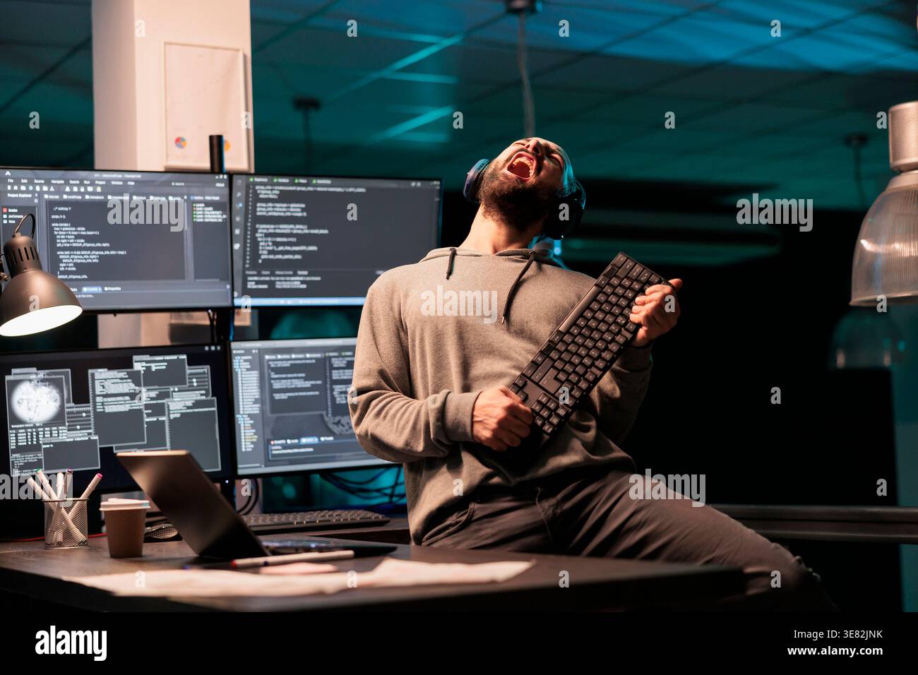 Database programmer playing guitar with keyboard, writing code with cloud computing and programming html source. Cheerful smiling developer having fun and acting silly in office. Stock Photo