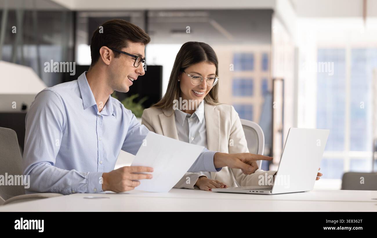 Business colleagues analyzing data together on laptop Stock Photo