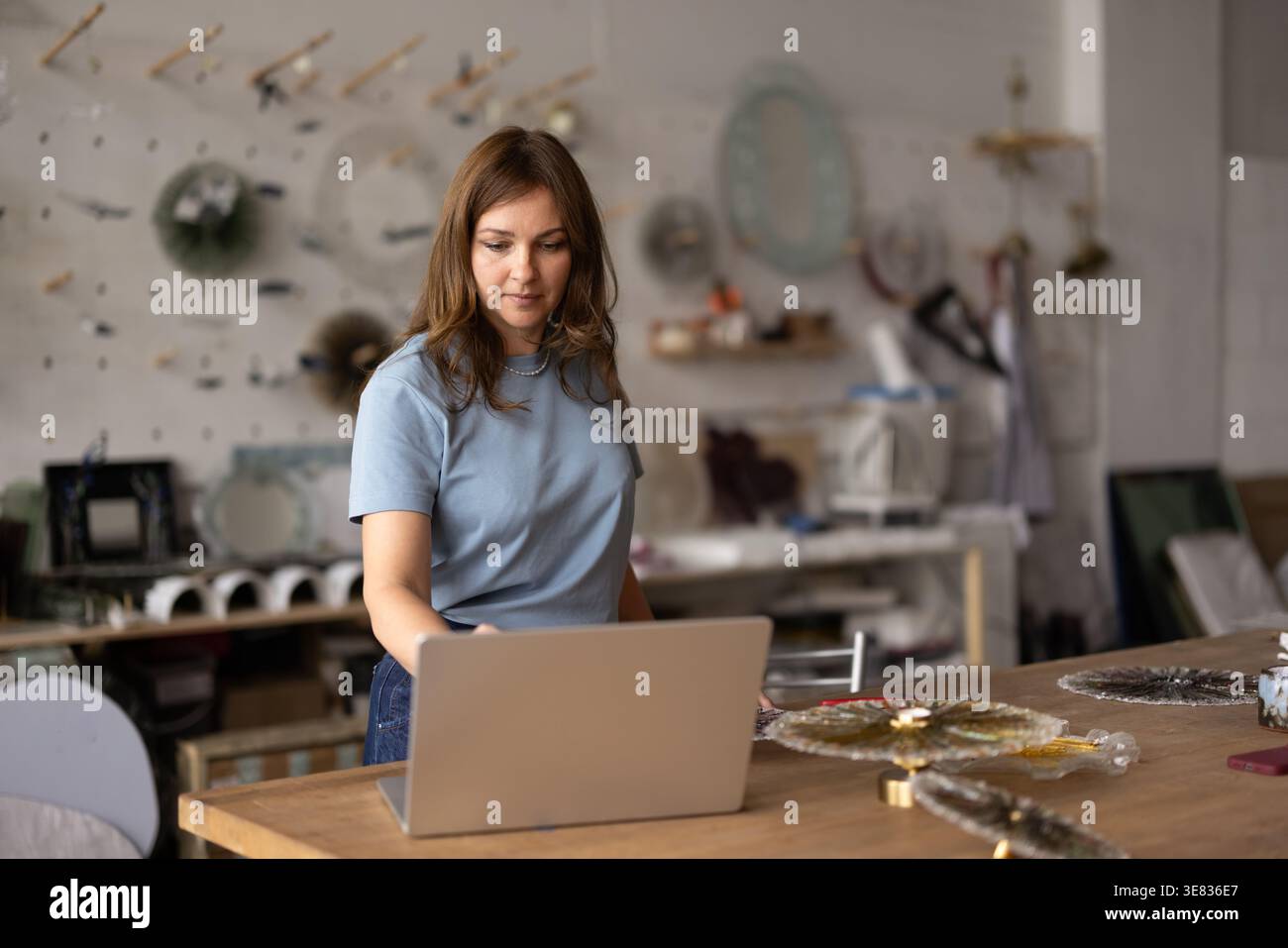Caucasian female artisan using laptop in creative workshop studio Stock Photo