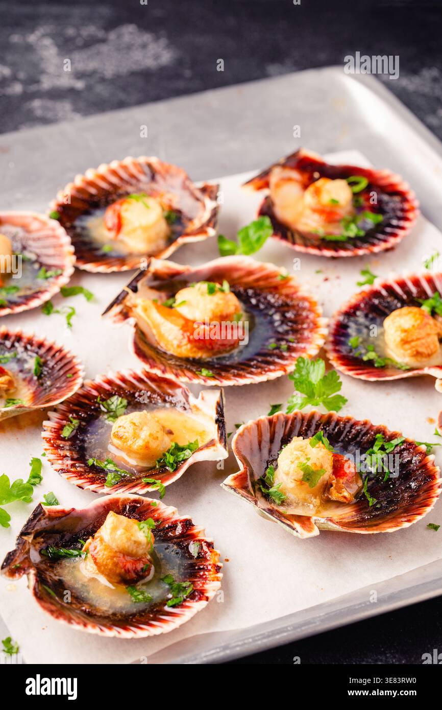 Cooked scallops with parsley on a baking sheet Stock Photo