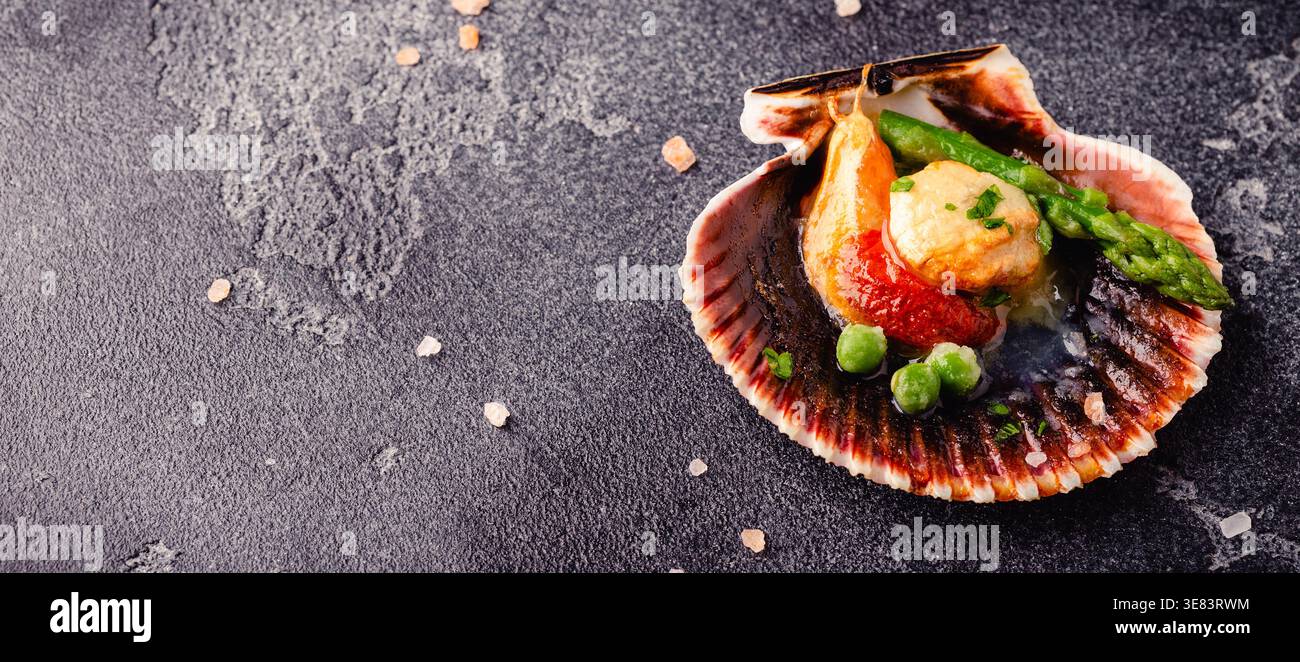 Cooked scallops with vegetables on a dark background Stock Photo
