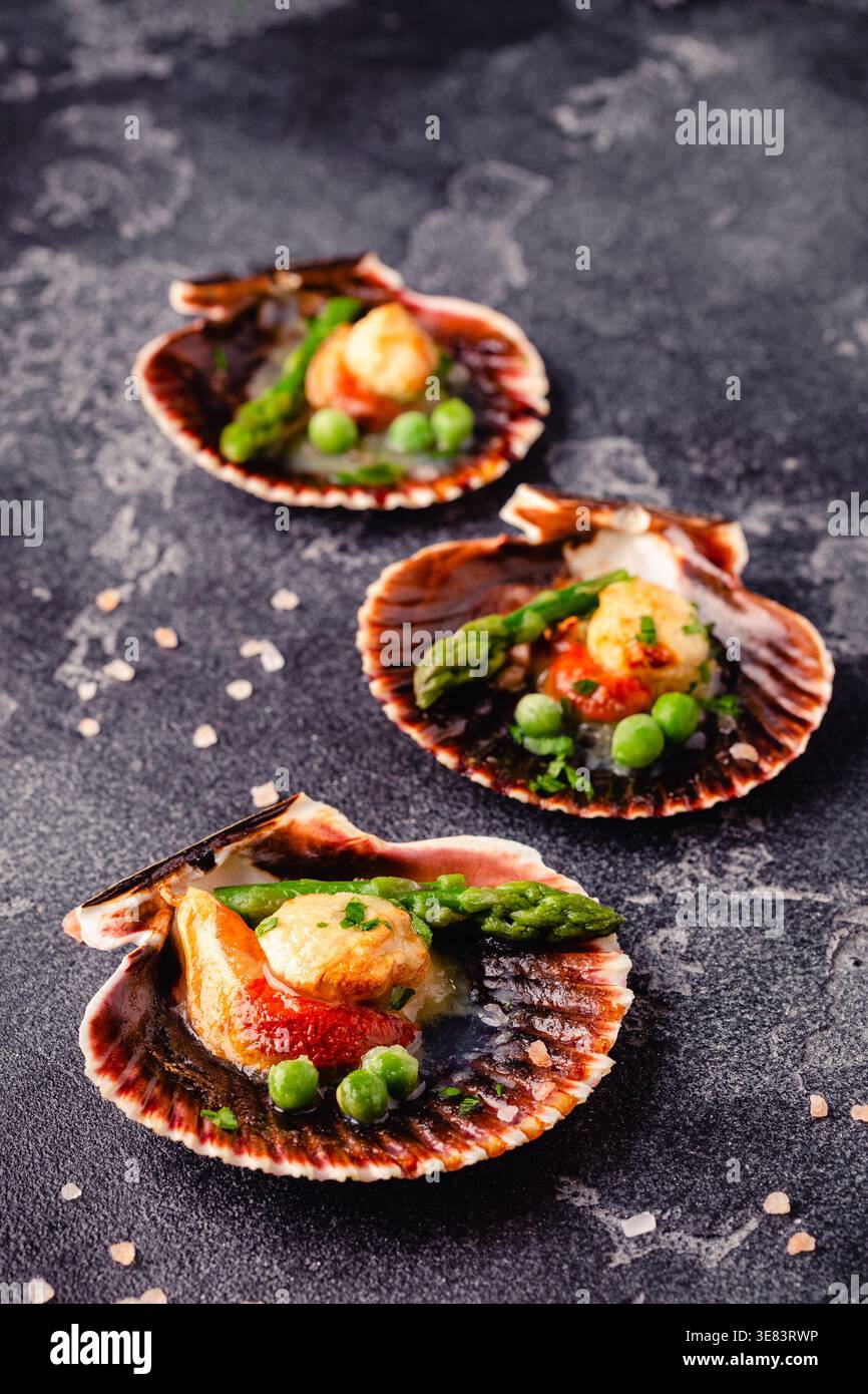 Cooked scallops with vegetables on a dark background Stock Photo