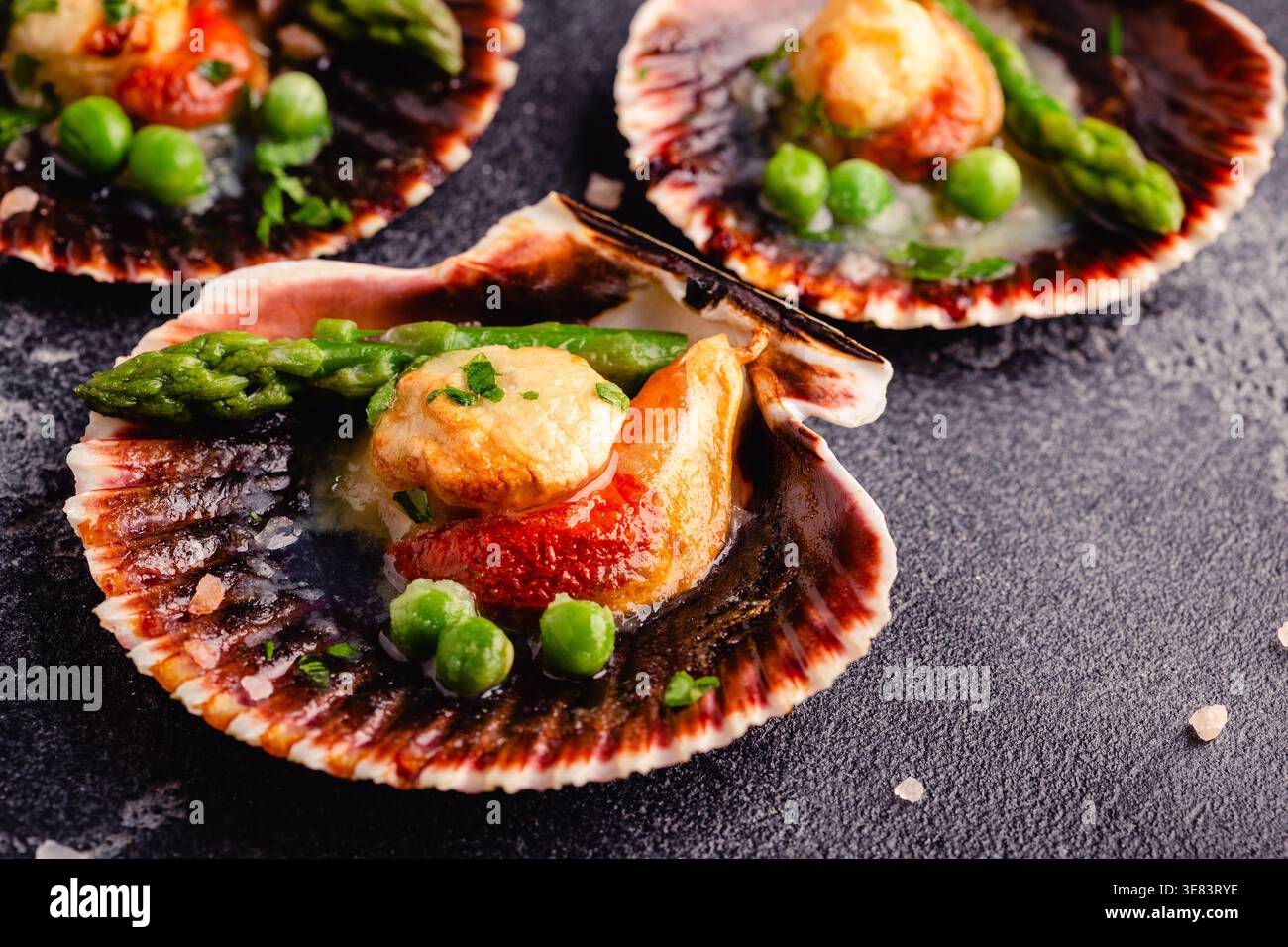 Cooked scallops with vegetables on a dark background Stock Photo