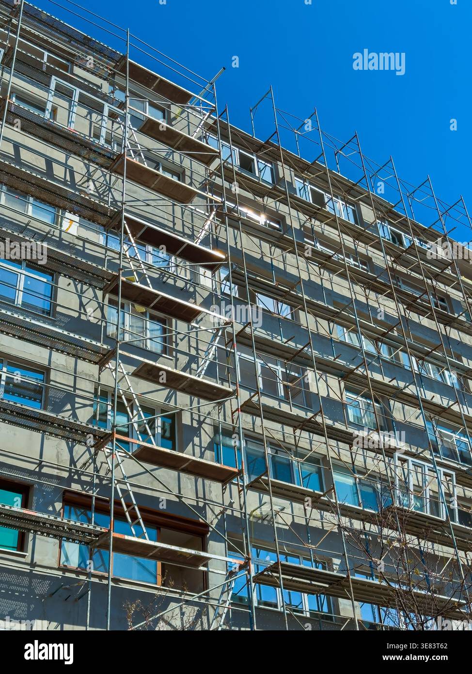 Workers conduct construction activities on a multi-story building ...