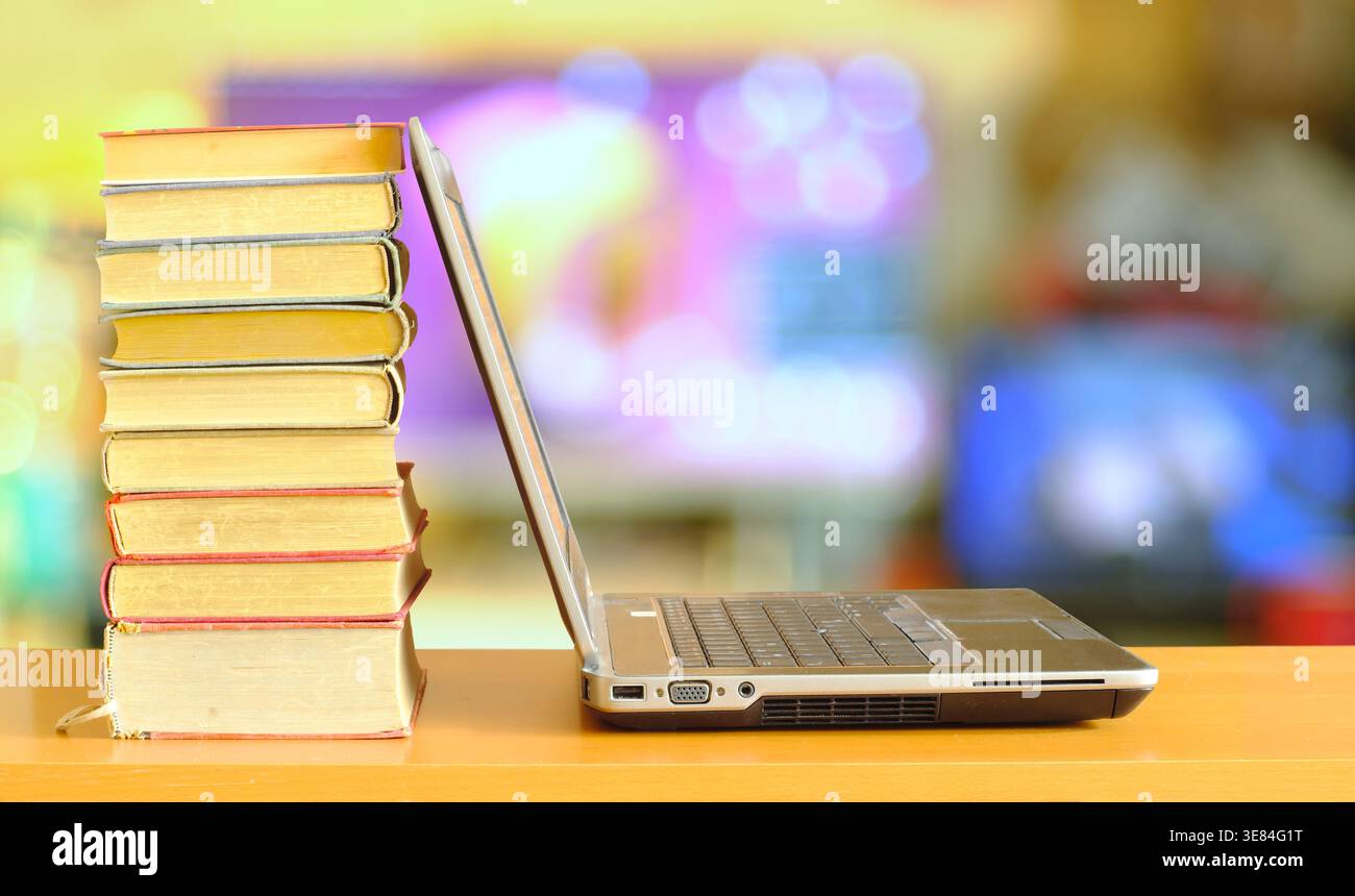 Laptop computer and stack of books ,blurred office in the background.Beat the clock,office work,research,education concept.Free copy space. Stock Photo