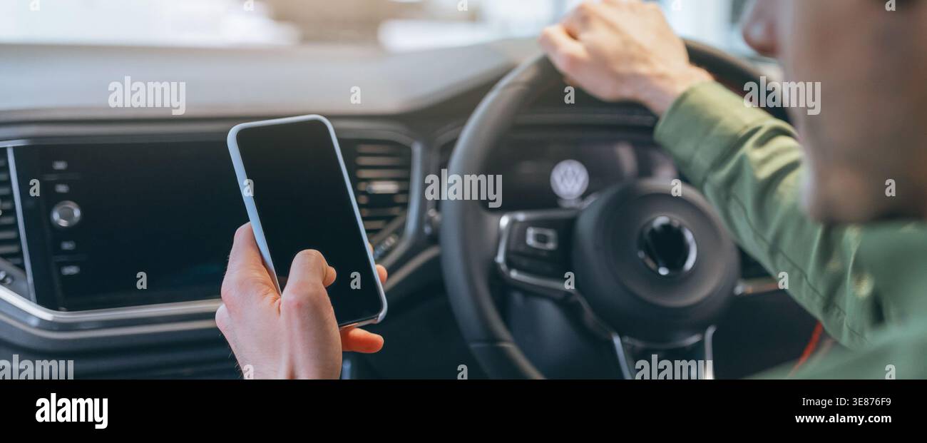 Man Using Smartphone While Driving in Modern Car Interior During Day Time Stock Photo