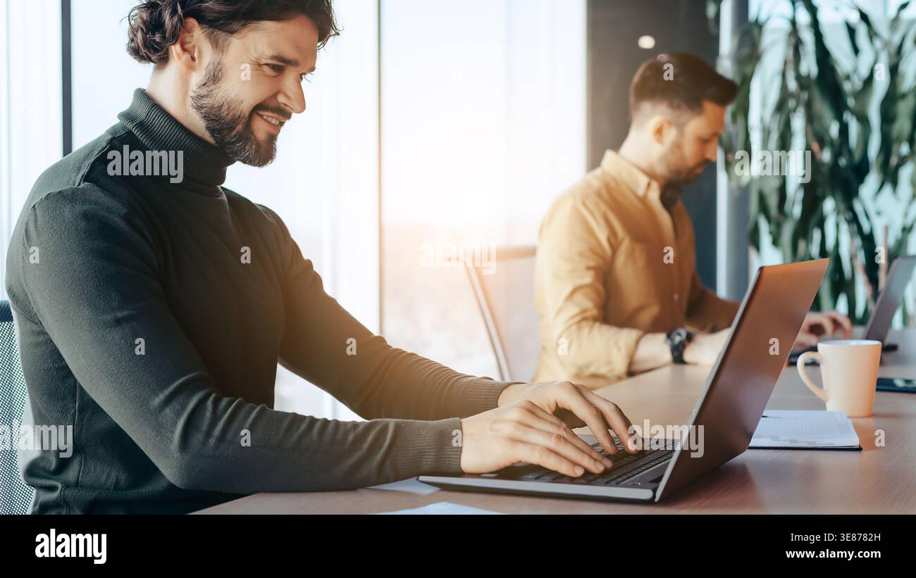 Two Men Working on Laptops in an Office During the Evening Stock Photo
