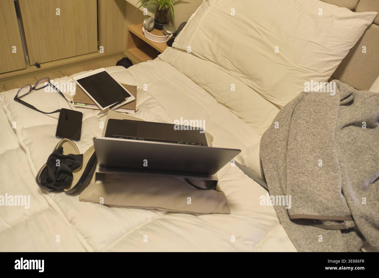 Digital devices creating a study and work area on a comfortable bed Stock Photo