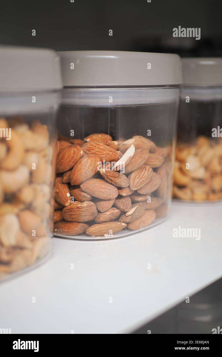 Different types of nuts in clear containers on a shelf Stock Photo