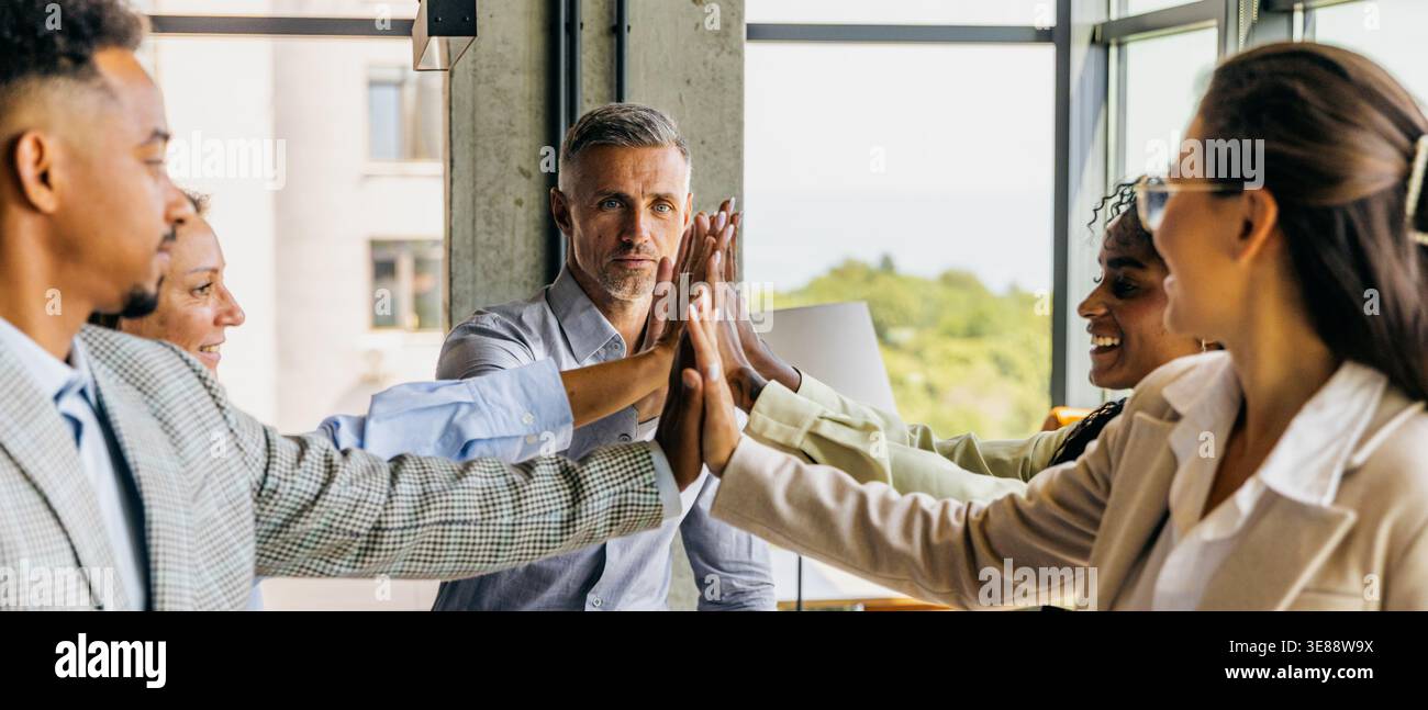 Energetic diverse group celebrates success with teamwork and joy Stock Photo
